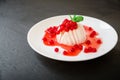 Pannacotta with berries on white plate at dark background