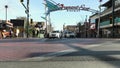 Panning footage of the Fremont East District sign with nightclubs, people walking, restaurants and cars driving on the street