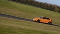 An orange Audi A3 sportscar speeding round corners