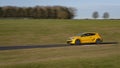 A yellow Renault Clio sportscar speeding round corners