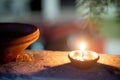 Panning shot of diya oil lamp casting light on a earthenware bird water feeder placed near plants on the hindu festival