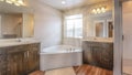 Pano Beautiful home bathroom with built in corner bathtub between two vanity units Royalty Free Stock Photo