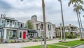 Pano Facade of elegant homes along street lined with palm trees against cloudy sky