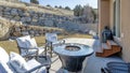 Pano Fire pit and paved patio at sunny backyard of house with stone retaining wall Royalty Free Stock Photo