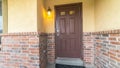 Pano frame Brown door with glass panels of a home with concrete and brick exterior wall