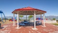 Pano frame Octagon shaped picnic pavilion with view of colorful playground and scenic lake Royalty Free Stock Photo