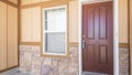 Pano Front door exterior of a house with half stone and wooden wall