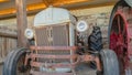 Pano Front of an old and vintage tractor against stone wall and roof of a farm barn