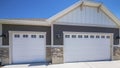 Pano Home exterior with white double garage doors with windows and half stone walls