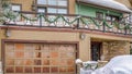 Pano Home with snowy yard and driveway in front of front door and metal garage door