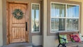 Pano House facade with an open porch and brown wooden front door with festive wreath