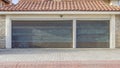 Pano House with metal doors on garage with red tile roof and brick paved driveway