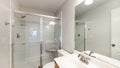 Pano Interior of a bathroom with wooden vanity sink with tile counter and shower stall with glass Royalty Free Stock Photo