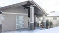 Pano Single storey family home with pitched roof and snow covered yard in winter