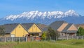 Pano Single storey houses against striking snow capped mountain and vibrant blue sky