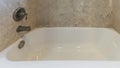 Pano Small space bathroom with ceramic bathtub and a wall mounted shower head and faucet Royalty Free Stock Photo