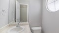 Pano Small white bathroom with marble top ceramic sink with blue cabinet and circular window Royalty Free Stock Photo
