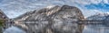 Pano view of snowy Austrian village Hallstatt by lake during sunset hour with clouds in winter