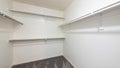 Pano White empty walk in closet with carpeted floor and shelves with metal hanging rods