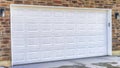 Pano White wooden garage door and wet driveway of home with snowy yard in winter