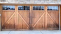 Pano Wide brown wood door with glass panes of attached garage of stone brick home Royalty Free Stock Photo