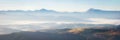 Panorama alpine landscape of the mountain peaks and valleys covered in fog at dawn. Spring landscape mountains and colorful