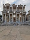 Panorama of the ancient library of Celsus in Ephesus with a girl in a blue dress. Turkey. UNESCO cultural heritage.