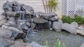 Panorama Artificial stone cascade waterfall in backyard on a sunny day