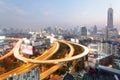 Panorama of Bangkok at dusk with skyscrapers in background and busy traffic on elevated expressways & circular interchanges