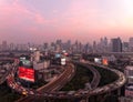 Panorama of Bangkok at dusk with skyscrapers in background & heavy traffic on elevated expressways & circular interchanges