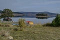 Panorama of Batak dam reservoir with island in the water and coastal autumn glade, cottage, forest, hill at Rhodope mountains