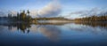 Panorama of blue lake in northern Minnesota with an island and pines on a foggy September morning Royalty Free Stock Photo