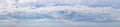 Panorama of blue sky with white clouds. Small white clouds stretch across the sky