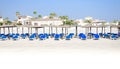 Panorama of blue sunloungers, palm trees and parasols