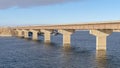 Panorama Bridge across blue lake with views of snow covered hills and cloudy blue sky