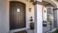 Panorama Brown wood arched front door with glass panes at the facade of home with porch