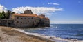 Panorama of Budva Old Town Citadel and Adriatic Sea with an outdoor cafe on Richard s Head beach in Montenegro, Balkans Royalty Free Stock Photo