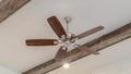 Panorama Ceiling fan with lights between decorative wood beams inside living room of home