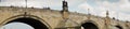 Panorama of the Charles Bridge in Prague, with statues on the side.