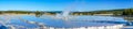 Panorama of circular tiered thermal pools reflecting the clear blue sky with a steaming center building pressure