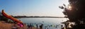 Panorama of the city beach with an inflatable slide and people, sand, sun, summer, the people are resting by the water