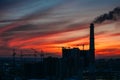 Panorama of city sunset and silhouettes of cranes, high-rise buildings and construction site with smoke Royalty Free Stock Photo