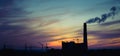 Panorama of city sunset and silhouettes of cranes, high-rise buildings and construction site with smoke Royalty Free Stock Photo