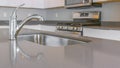 Panorama Close up of a glossy countertop with faucet and sink inside a modern kitchen