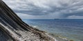 Panorama of a cloudy seascape. A picturesque stone wild beach at the foot of the rocks in rainy weather and a ship on the horizon Royalty Free Stock Photo