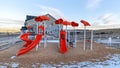 Panorama Colorful playground with snow on the ground against homes and vast cloudy sky