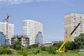 Panorama construction. Car crane on the background of beautiful buildings, green spaces and a blue sky Royalty Free Stock Photo