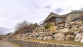 Panorama crop Dirt road along homes on a slope with huge rocks and concrete retaining wall Royalty Free Stock Photo