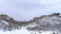 Panorama crop Homes atop gentle hill slopes with fresh snow and leafless bushes in winter Royalty Free Stock Photo