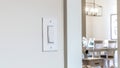 Panorama crop Wall mounted electrical rocker light switch with blurry dining room background